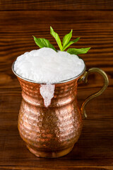 Turkish buttermilk in a copper cup on wooden background. Turkish yogurt drink