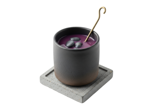 Dark stoneware mug with murky deep violet elixir, submerged river stones, and antique bronze stirring rod on a concrete coaster, against a transparent background. Quiet mysticism and alchemical