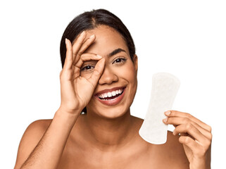 Filipino woman with sanitary pad in studio excited keeping ok gesture on eye.