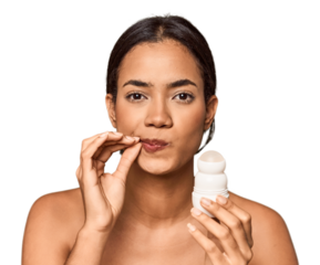 Filipino woman holds deodorant in studio with fingers on lips keeping a secret.