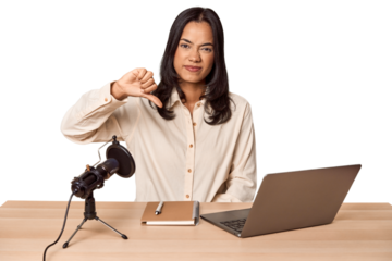 Woman records podcast with laptop showing a dislike gesture, thumbs down. Disagreement concept.