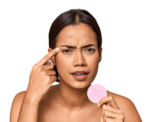 Woman holds facial sponge in studio showing a disappointment gesture with forefinger.