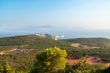 Coastal view with green hills and distant lighthouse