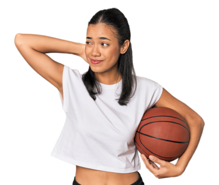 Young Filipino woman with basketball touching back of head, thinking and making a choice.