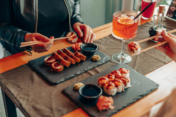 Friends Sharing Sushi Rolls with Cocktail in Restaurant