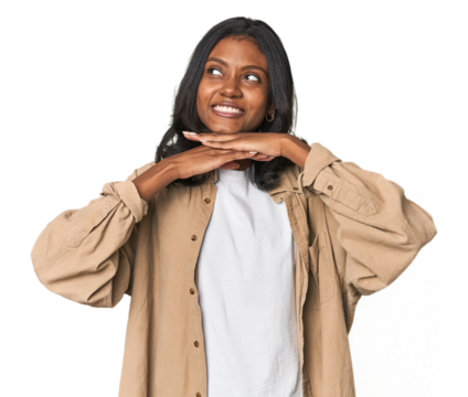 Portrait of a young Indian woman keeps hands under chin, is looking happily aside.