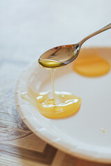 Golden Honey Dripping from Spoon onto Plate