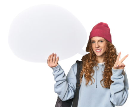 Redhead holding a comic speech bubble joyful and carefree showing a peace symbol with fingers.