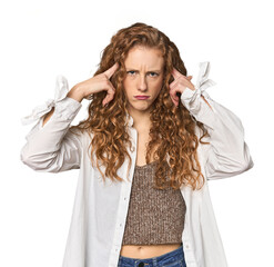 Simple redhead studio portrait focused on a task, keeping forefingers pointing head.