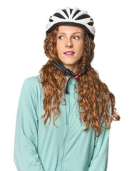 Young redhead cyclist in helmet and gloves, studio shot