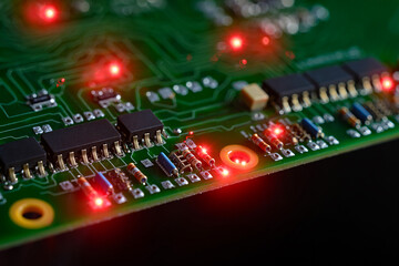 Close-up of a green circuit board with glowing red LE Ds