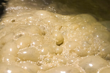 Bubbles of foam in the dirty water of gold ore tank.