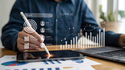 Close-up of a person using a stylus on a tablet displaying financial charts and data analysis with digital overlays enhancing the technology and business concept