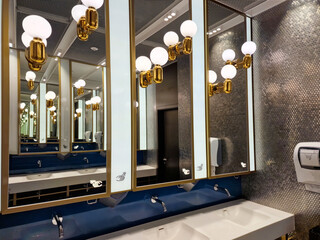 This restroom showcases a chic design with decorative mirrors, gold accents and modern lighting