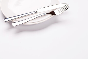 Fork and knife on an empty plate with copy space