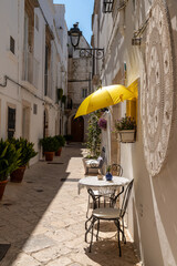 Metal chairs and yellow umbrella in narrow alley