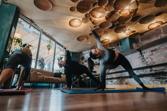 A group of individuals practicing yoga in an indoor environment with warm lighting and cozy surroundings, highlighting flexibility, mindfulness, and relaxation.
