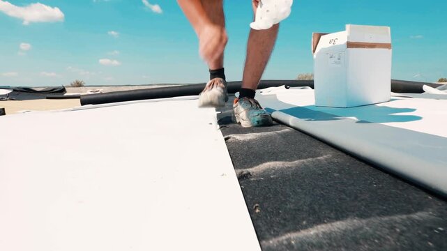 Construction worker installing pvc roofing membrane on flat roof