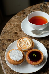 tart citron, amandine and Mirliton d'Amiens and cup of tea on the marble table
