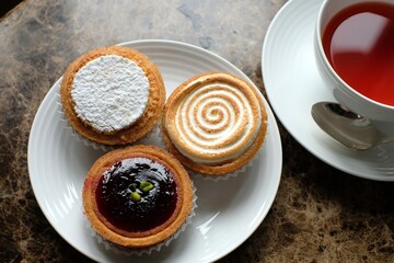 tart citron, amandine and Mirliton d'Amiens and cup of tea on the marble table
