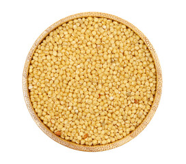 Peeled, uncooked yellow millet seeds in bamboo bowl, organic food product isolated on white background, top view 
