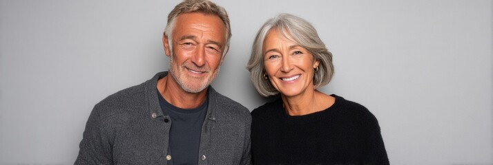 A joyful senior couple poses together in a studio setting, showcasing their happiness and connection. Ideal for themes of love and companionship.