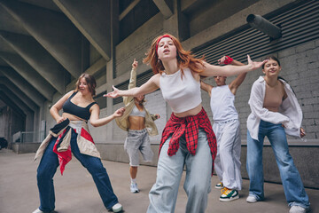 Redhead female dancer moving forward with confidence during street choreography. Concept of youth...