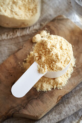 Whey protein powder in a white plastic measuring scoop