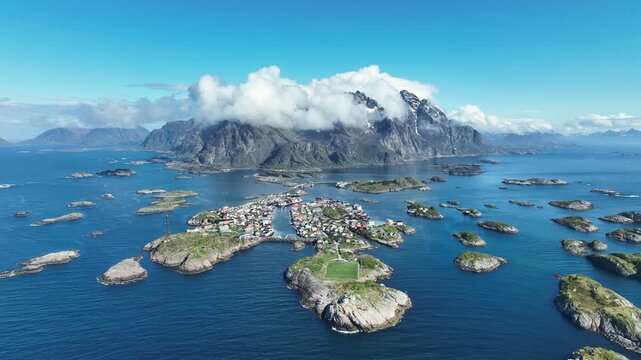 Wide high aerial of Henningsvaer with football field, islands, sea and mountain panorama
