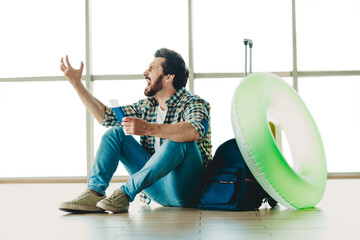 Excited traveler holding his ticket in an airport terminal, ready for his holiday adventure,...