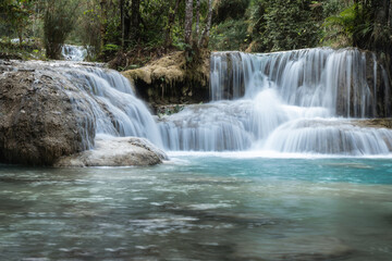 Obraz premium Kuang Si Waterfall flowing into a clear blue forest river in Luang Prabang, Laos