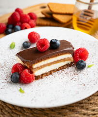 Lotus cream and biscuit cake with a chocolate and red berry topping.