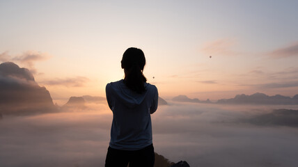 Person watching sunrise over foggy mountains in peaceful outdoor setting  at  Phadeng Peak, Luang Prabang, Laos