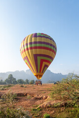 Colorful hot air balloon preparing for takeoff in open field with mountains
