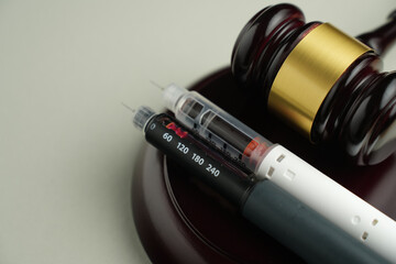 Semaglutide injection pen with judge gavel – legal and ethical debate in medicine