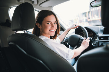Young woman smiling while driving a car on a sunny day, enjoying a weekend getaway