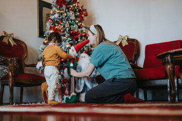 A mother kneels to interact with her child beside a festive Christmas display, creating a warm...