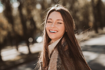 Chic woman enjoying an autumn day with sunlight and natural beauty in an urban park setting,...