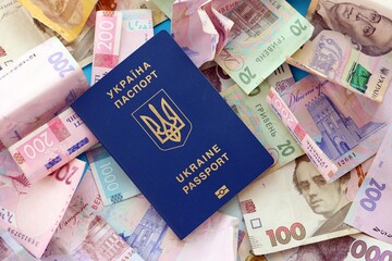 Ukrainian biometrical passport lies on big amount of different ukrainian hryvnia money bills
