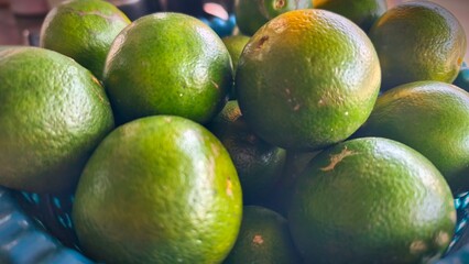 Close-up of Fresh Green Limes in a Basket, Vibrant Green Limes Piled High in a Blue Plastic Basket