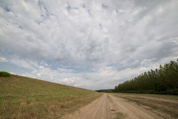 Rural dirt road leading to horizon under dramatic morning sky