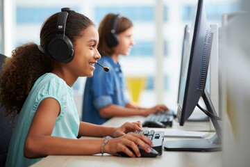 Young students learning computer skills with headphones in a classroom environment today