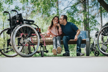 A happy couple enjoying time together outdoors in a wheelchair-accessible park. They are seated on...