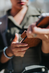 Focused view of hands holding and using a smartphone outdoors under clear, sunny skies. A casual setup showcasing modern technology and communication in an urban daily life setting.