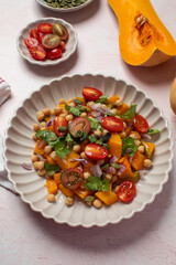 Fresh chickpea and pumpkin salad with tomatoes and herbs for healthy eating. Autumn salad