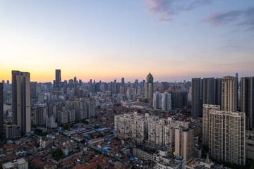 Wuhan China cityscape at sunset with towering buildings stretching across the vast urban landscape, reflecting the vibrant evening sky above the region near the Yangtze River.