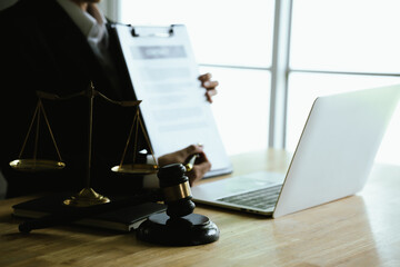 A lawyer reviews a contract document at a desk with a gavel, scales of justice, and a laptop, symbolizing law, legal advice, agreements, and professional consultation.