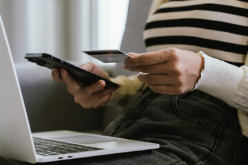 A young woman uses a laptop and credit card for online shopping, symbolizing modern finance, digital payments, e-commerce, banking, and technology-driven consumer lifestyles in today’s connected world