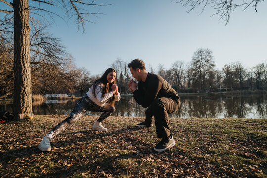 A couple engages in fitness exercises near a scenic lake at sunset, enjoying nature and bonding while performing stretching routines in a peaceful outdoor location.