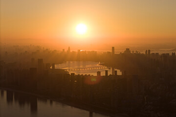 Fototapeta premium Morning sun rises above the Wuhan China city skyline, creating a beautiful golden glow over modern buildings and reflecting on the expansive Yangtze River.
